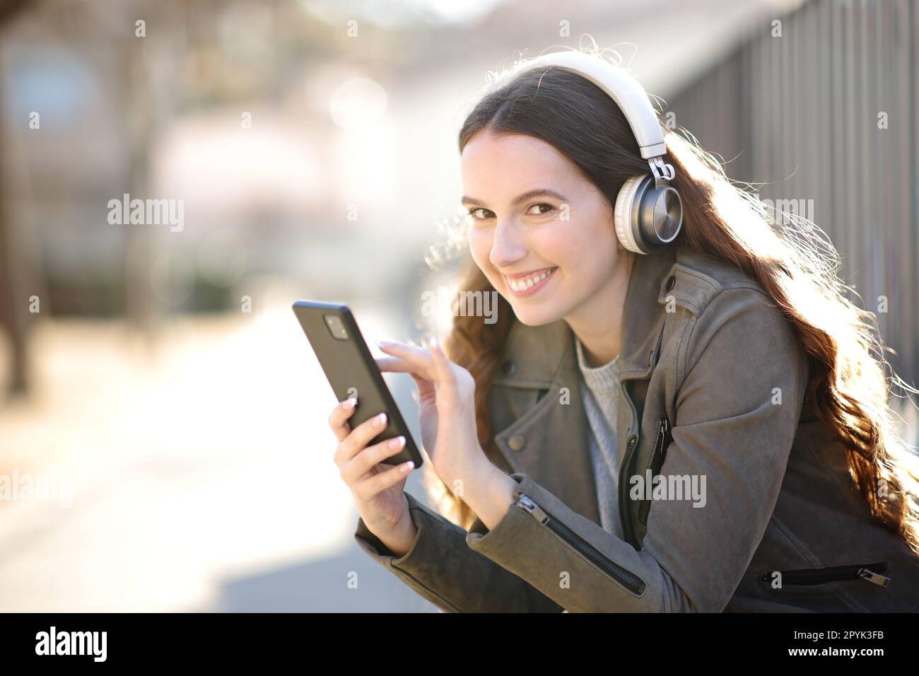 Une femme heureuse te regarde en écoutant de l'audio Banque D'Images