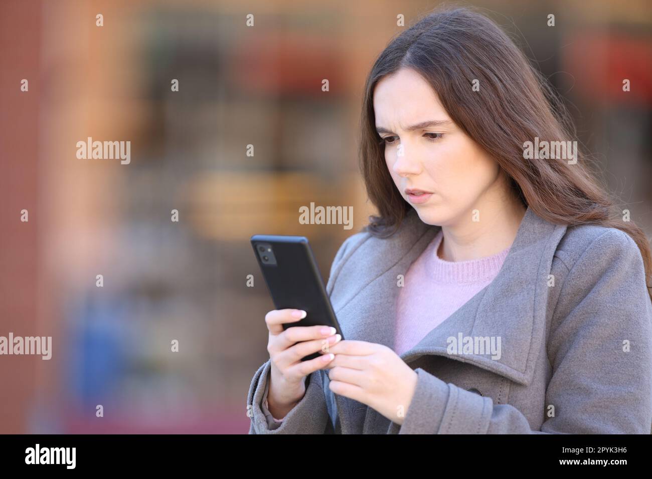 Femme inquiète utilisant le téléphone dans la rue en hiver Banque D'Images