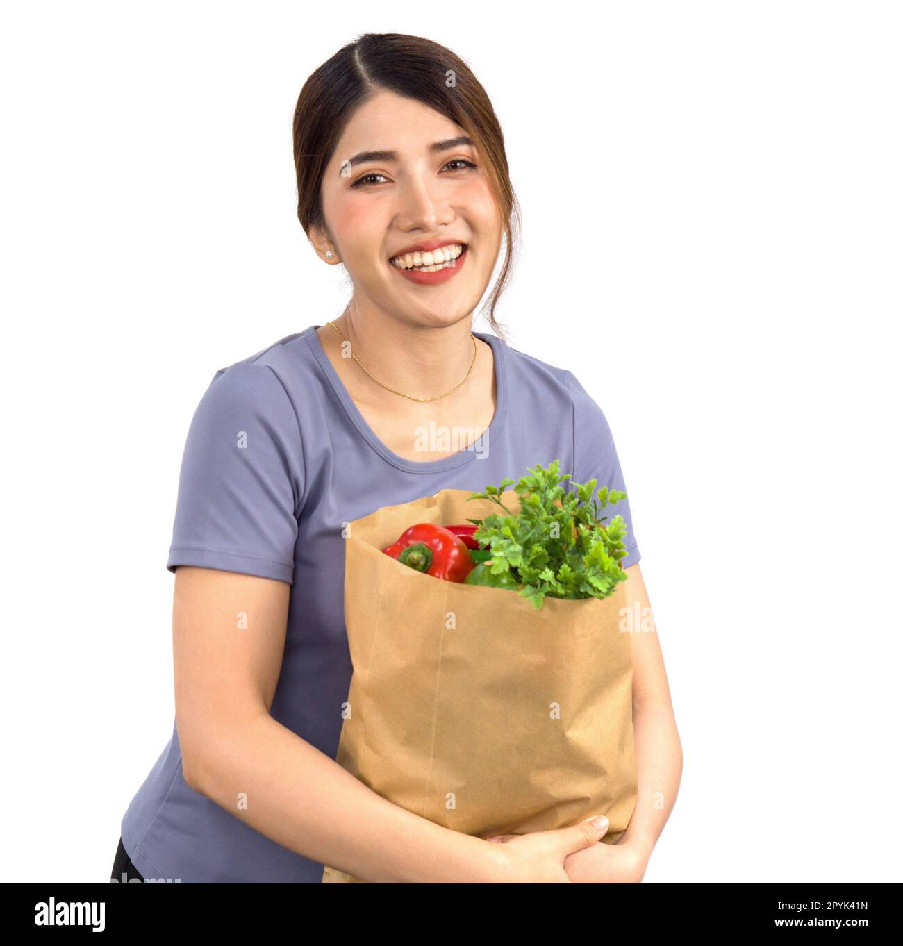 Jeune femme asiatique en tenue décontractée stand avec un sourire, tenant le sac de papier plein de légumes. Banque D'Images