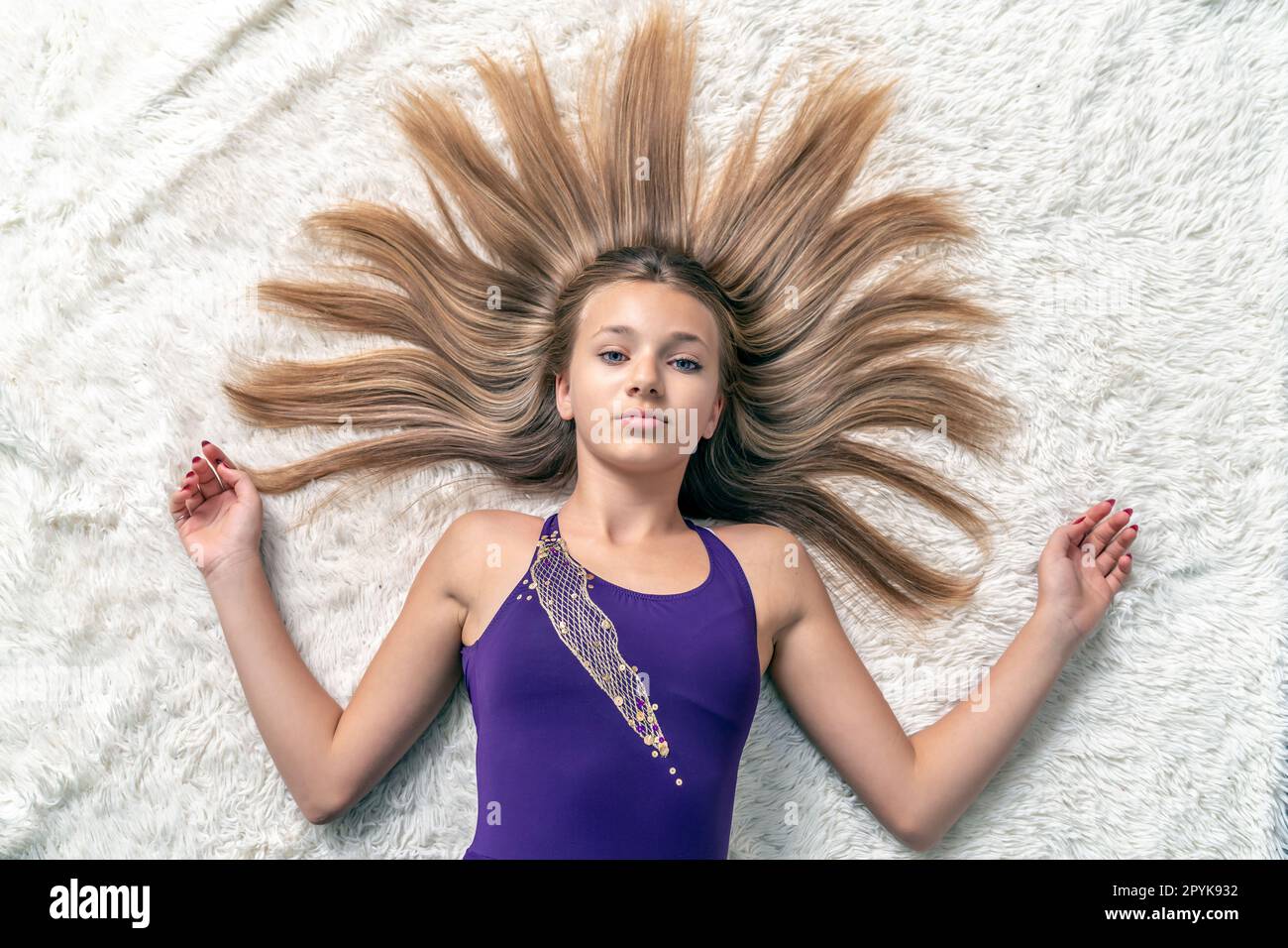 une adolescente avec des cheveux amples en forme de soleil est couché sur un tapis blanc Banque D'Images