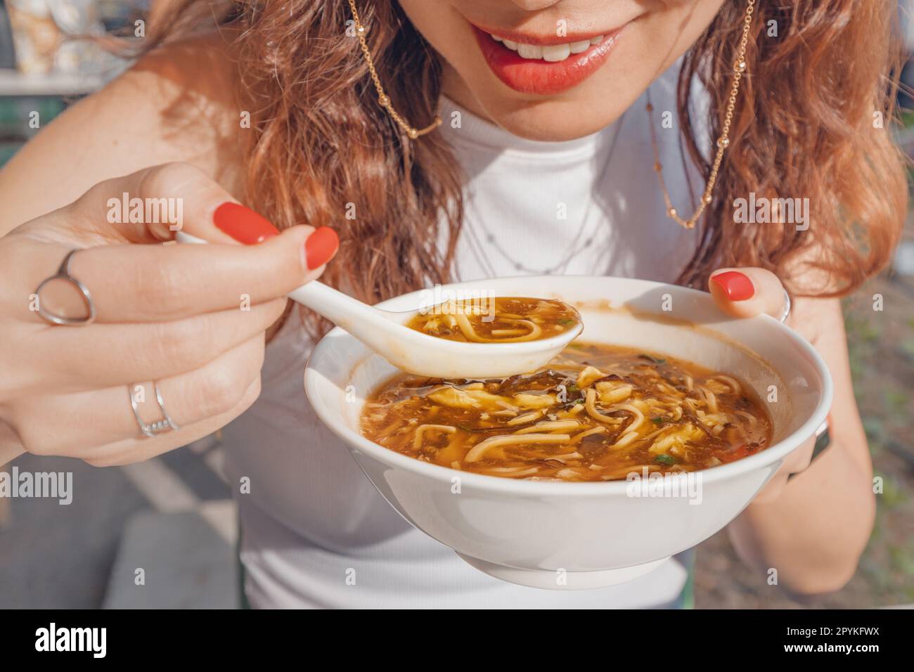 Une fille mange de la soupe chinoise aigre et chaude ou de la soupe épicée de Taïwan avec des ingrédients frais sur une assiette au restaurant. Cuisine et plats asiatiques traditionnels Banque D'Images