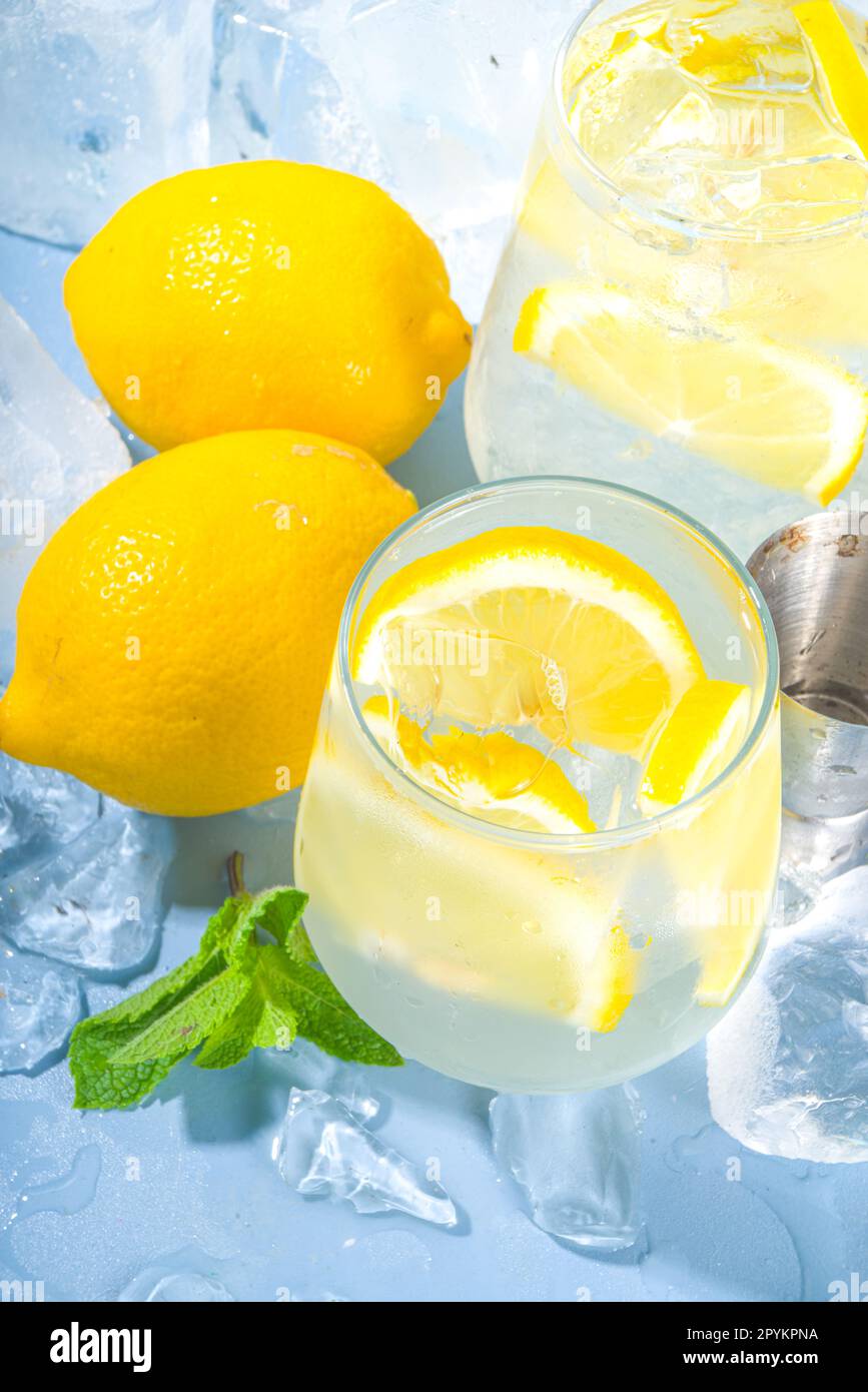 Limonade à cocktail traditionnelle fraîche d'été, avec des tranches de citron et beaucoup de glace pilée et des tourteaux glacés sur fond bleu Banque D'Images