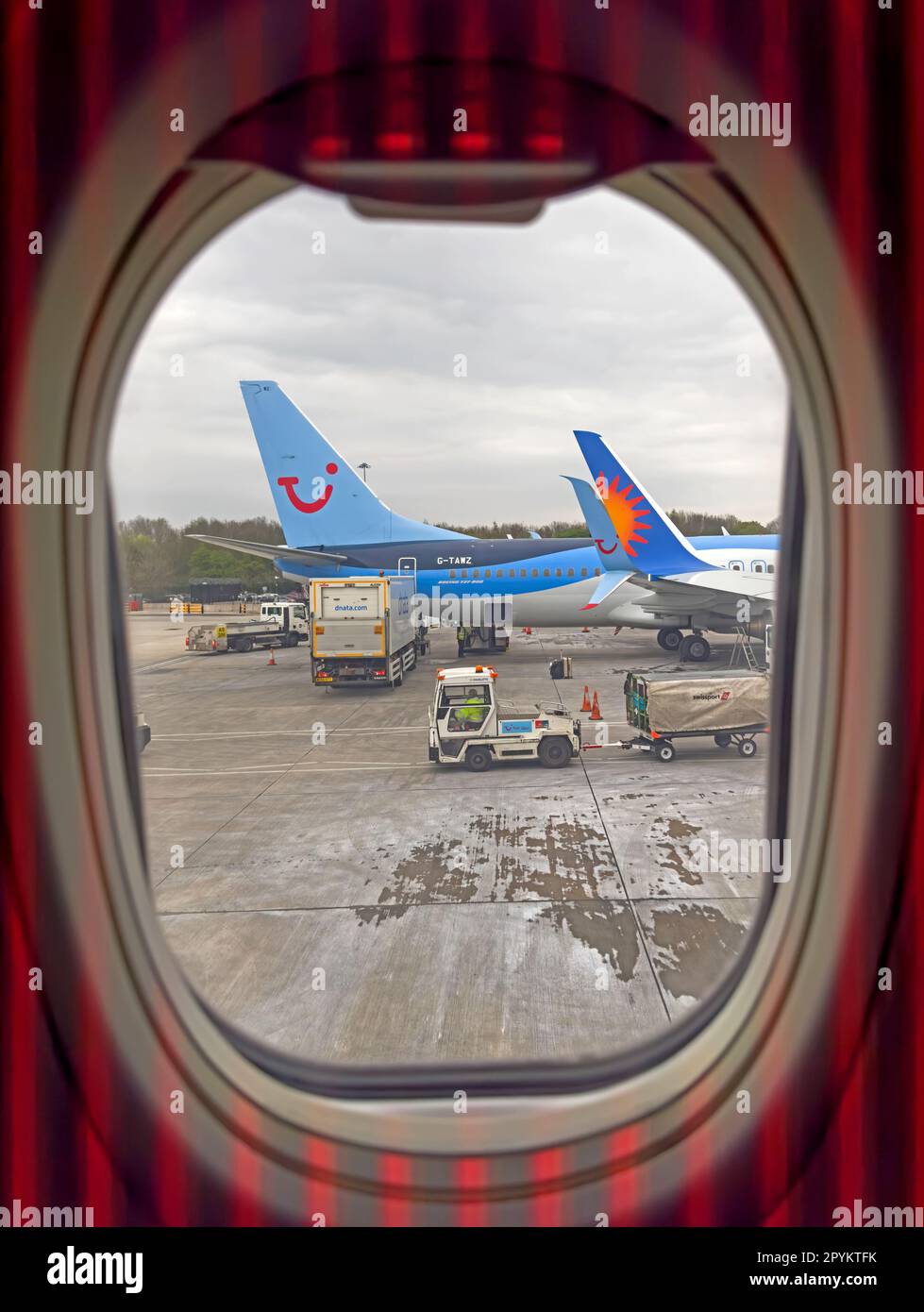 Vue fenêtre d'un avion de location de vacances Jet2, Tui Holiday et d'autres charter ayant des bagages de soute chargés Banque D'Images