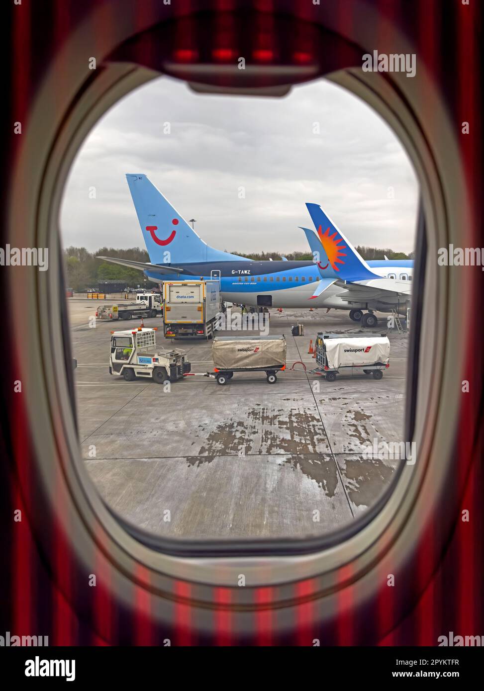 Vue fenêtre d'un avion de location de vacances Jet2, Tui Holiday et d'autres charter ayant des bagages de soute chargés Banque D'Images