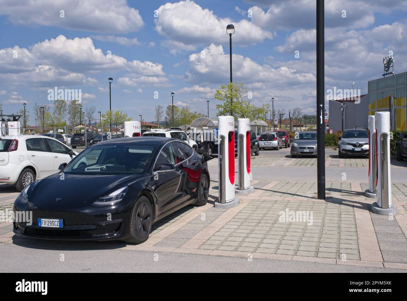 Mondovi, Italie - 18 avril 2023: Un cliché statique d'un solide noir Tesla modèle 3 de charge de moteur double au Mondovi Supercharger dans une journée ensoleillée de printemps. S Banque D'Images