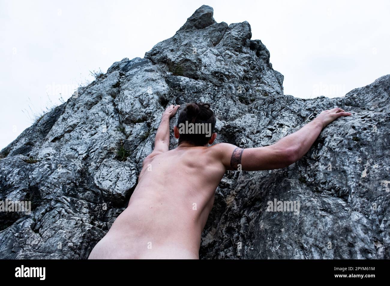 Homme grimpant nu sur le rocher Banque D'Images