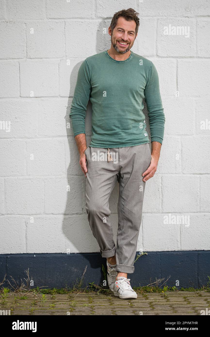 Portrait regardant l'appareil photo d'un homme adulte à barbe gai portant des vêtements décontractés contre un mur blanc. Un homme mûr souriant pose une photo Banque D'Images