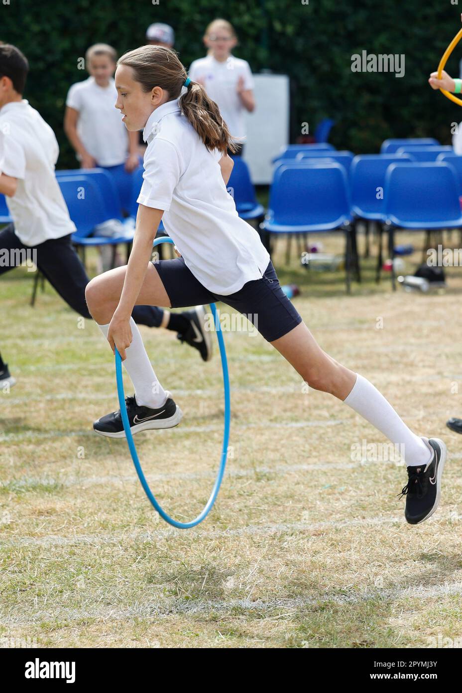 Jeune fille qui court dans une course de cerceau à la School Sports Day, Essex, Angleterre Banque D'Images