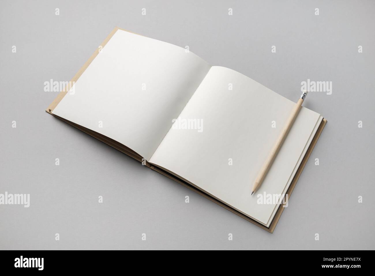 Carnet d'esquisses ouvert vierge et crayon sur fond de papier gris. Modèle de conception réactif. Banque D'Images