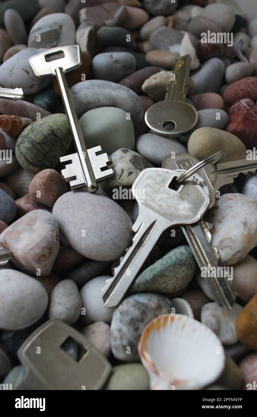 Des paquets de clés et des clés simples sont dispersés dans un mess sur la photo de stock verticale de pierres Banque D'Images