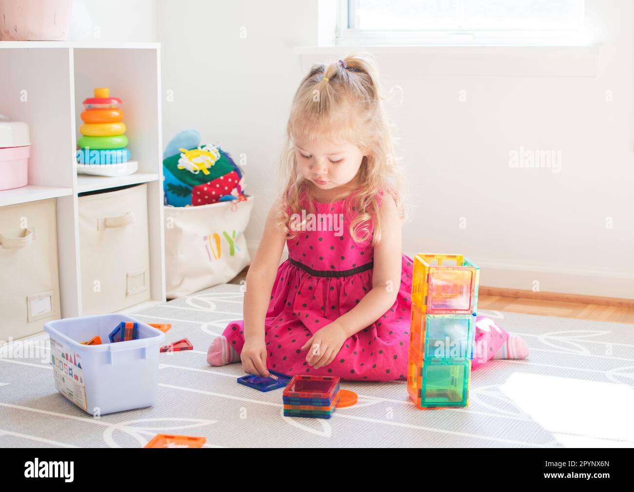 Petit enfant jouant avec des tuiles aimantées. Tout-petit caucasien fille jouant. Banque D'Images