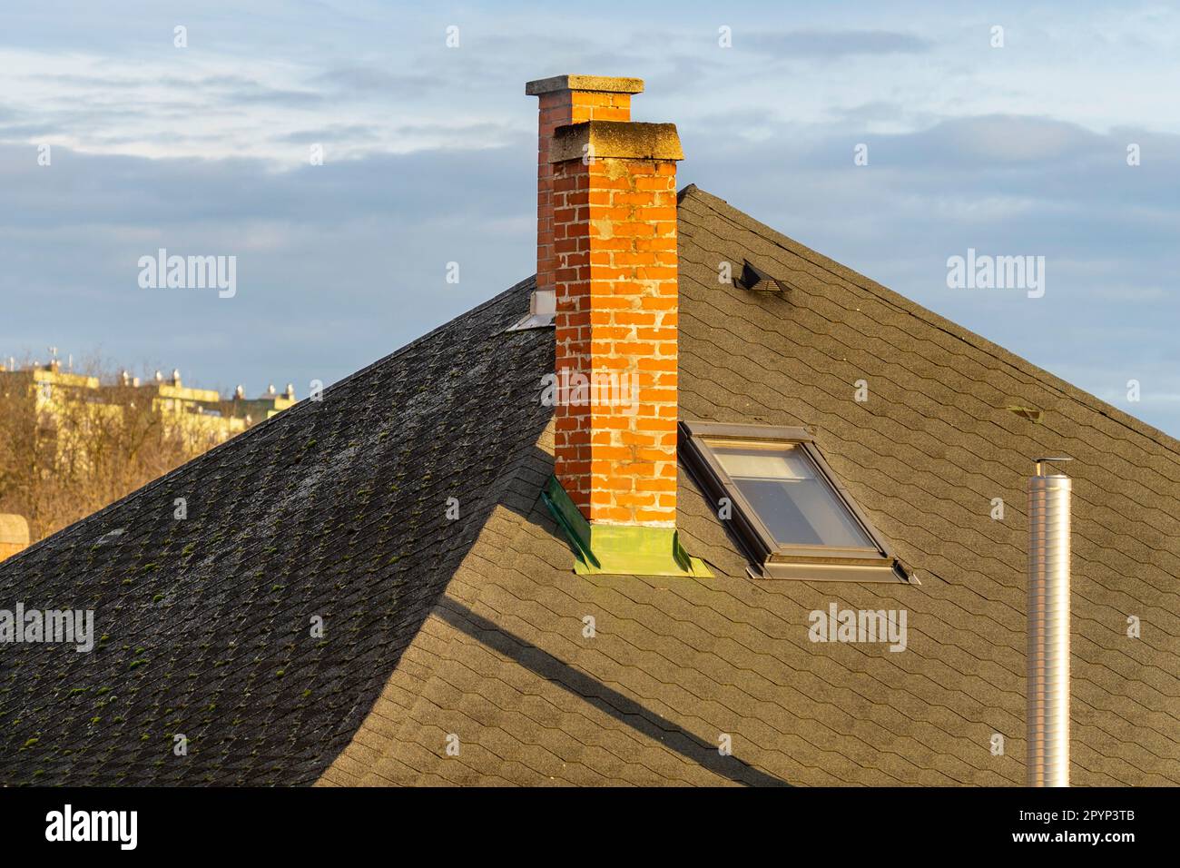 Cheminées en briques et cheminée en métal sur le toit d'une maison avec une lucarne Banque D'Images