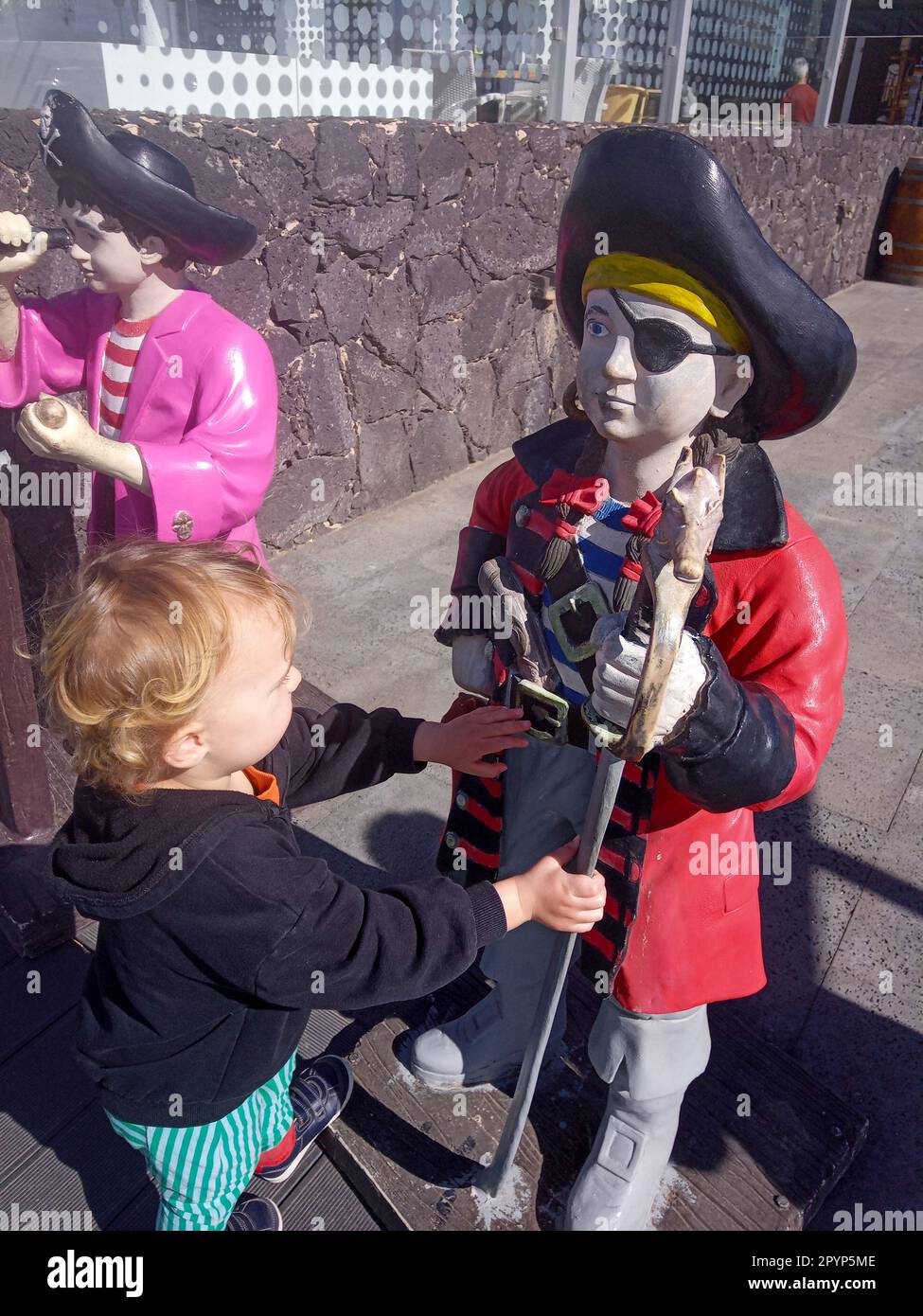 Un enfant caucasien qui interagit avec une statue en plastique ressemblant à un enfant pirate à l'extérieur d'une boutique de gif comme image publicitaire. Banque D'Images