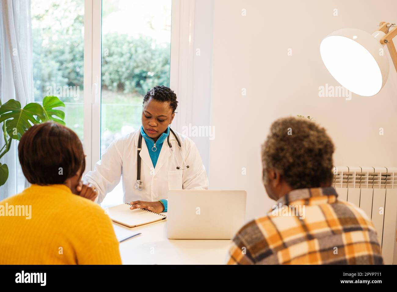 Une femme médecin passe la consultation à un couple senior dans son bureau. Concept : diagnostic, soins de santé, maladie Banque D'Images