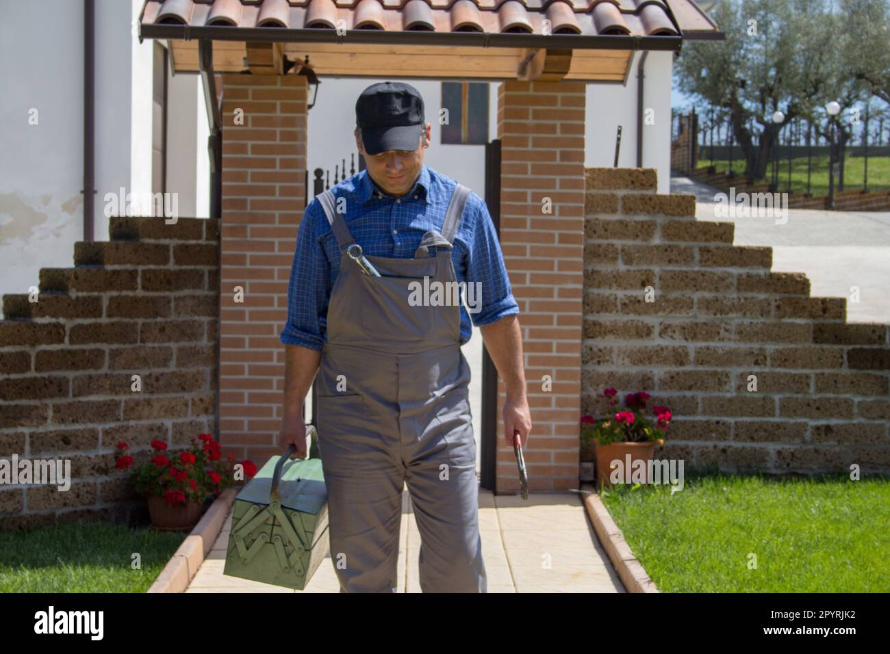 Image d'un homme à main dans des salopettes et une boîte à outils sur son  chemin vers une maison après un appel. Travaux de réparation bricolés d'un  plombier et d'un électricien Photo