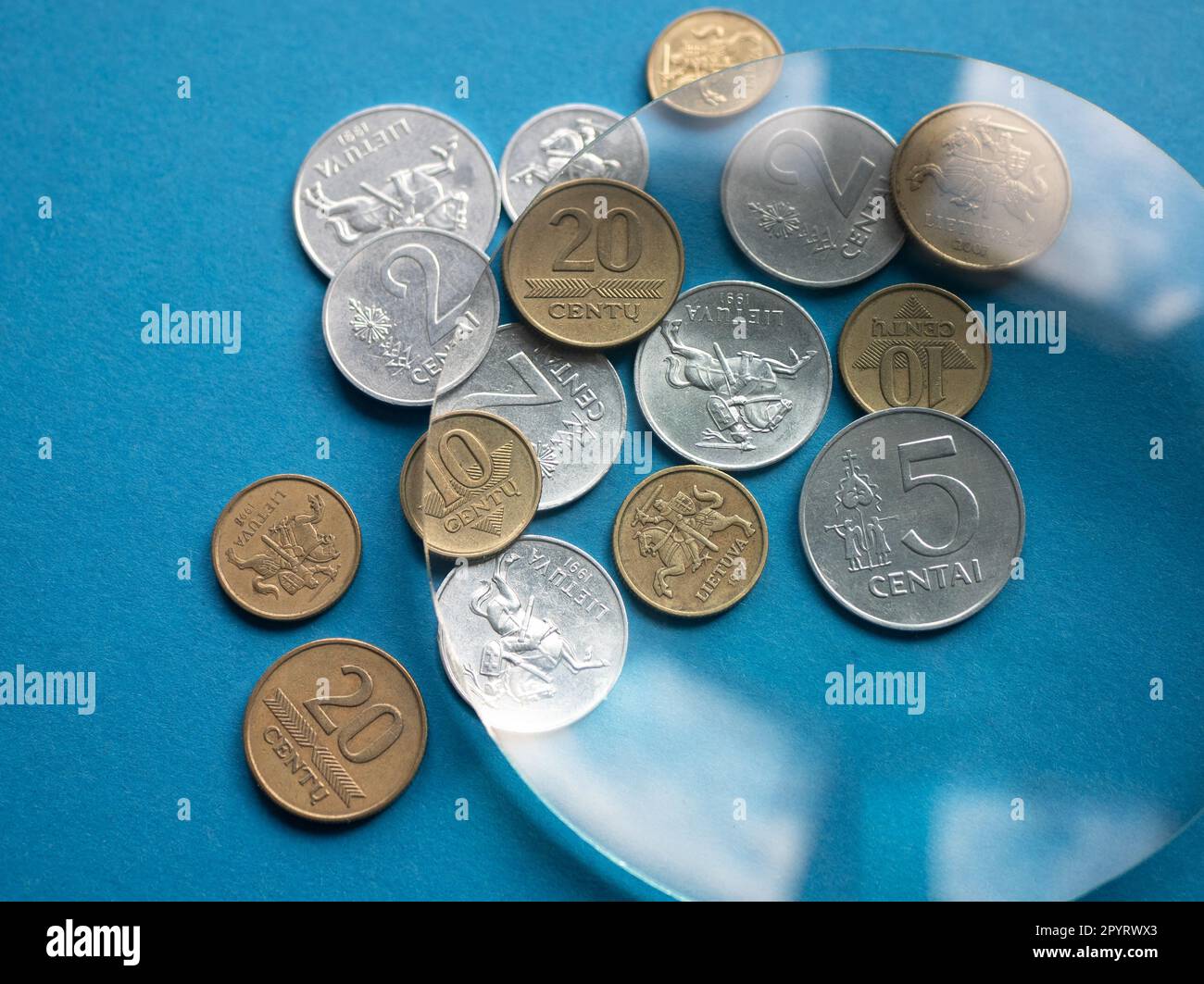 Vieux argent métallique lituanien sous loupe sur fond bleu, gros plan. Concept de devises locales Banque D'Images