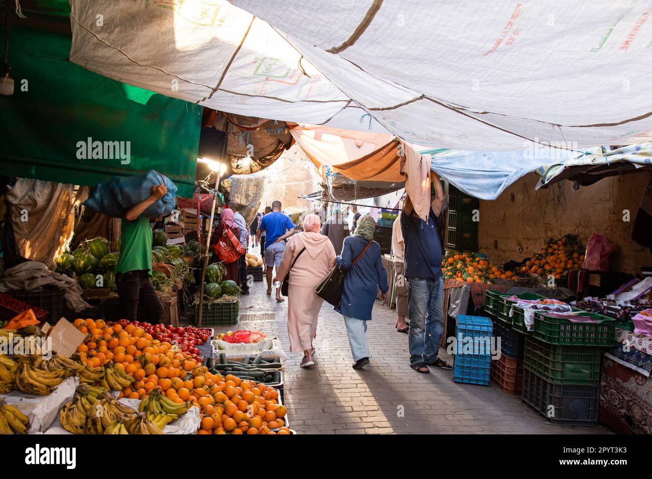 Fès, Maroc 2022: Rues étroites historiques et traditionnelles de Fès el-Bali, la vieille médina, avec des magasins de légumes dans le souk (suq) et des gens Banque D'Images