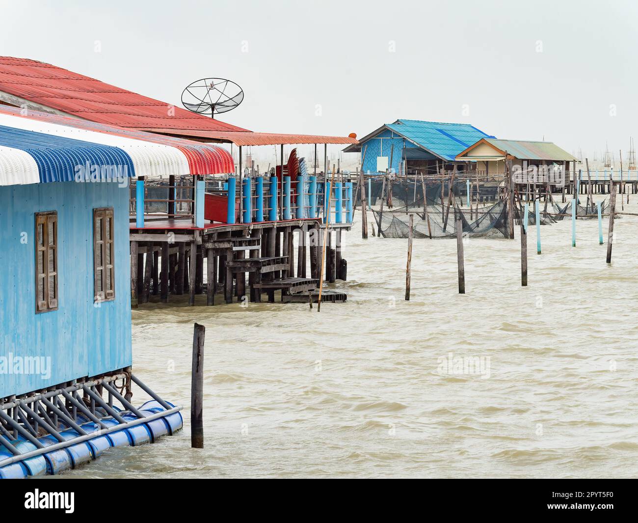 Ferme piscicole avec des maisons de pêcheurs au lac Songkhla à Songkhla, au sud de la Thaïlande, le jour des pluies. Banque D'Images