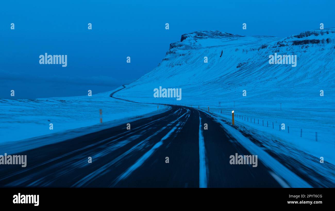 Route d'hiver avec montagne enneigée pendant l'heure bleue Banque D'Images