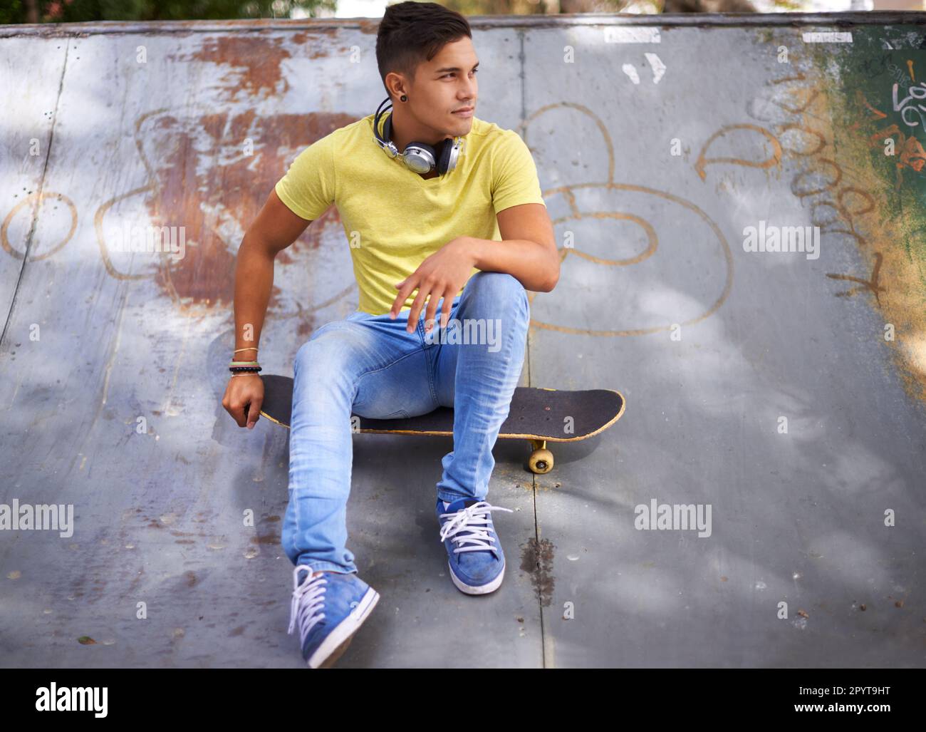 Juste moi et mon conseil. un jeune homme assis sur son skateboard dans un parc de skate. Banque D'Images