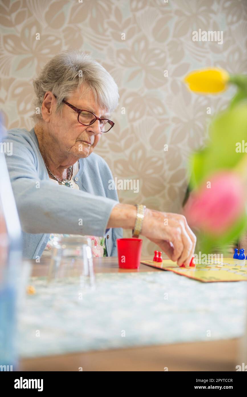 Senior woman playing crokinole en rest home Banque D'Images