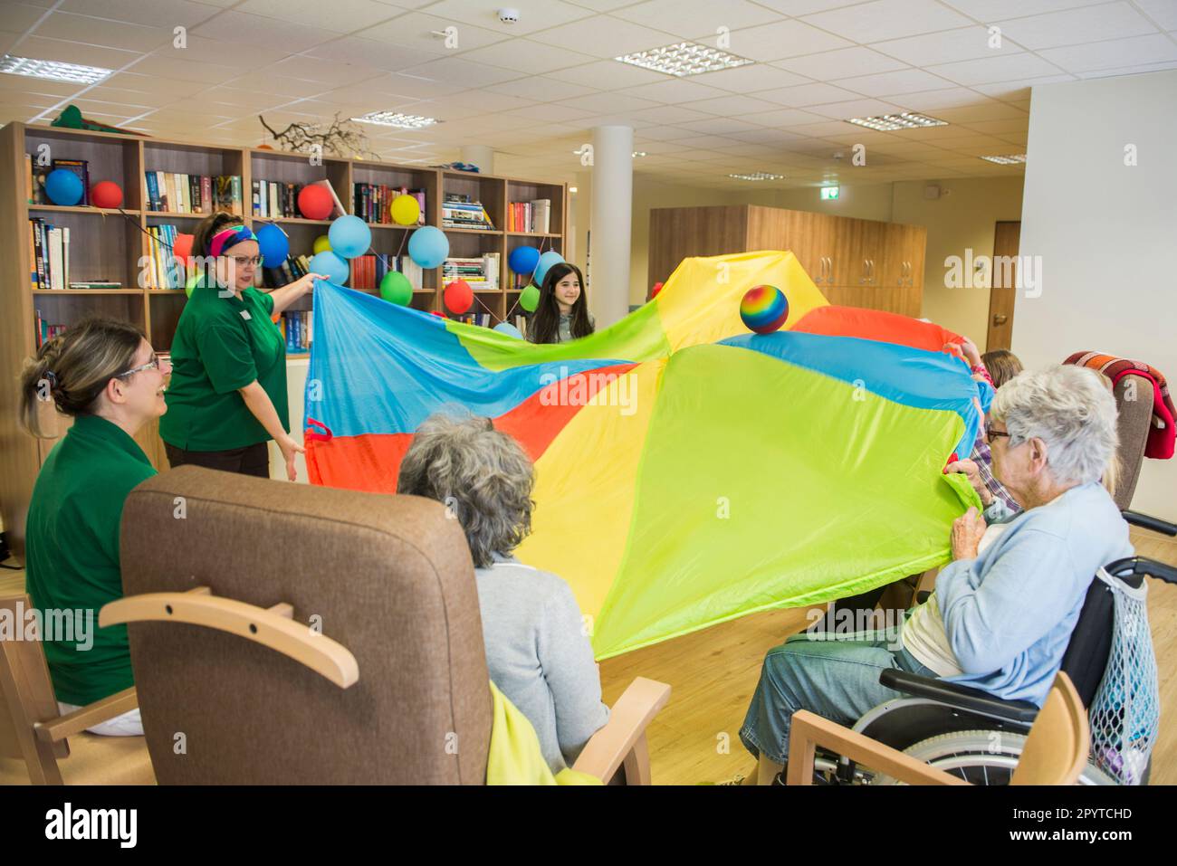 Personnel infirmier avec des filles et des femmes âgées faisant de l'exercice sportif en utilisant le parachute et le ballon dans la maison de repos Banque D'Images