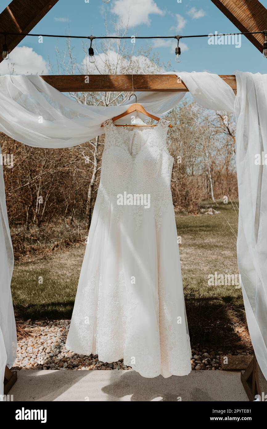 Robe de mariage en dentelle pleine longueur suspendue au soleil de printemps Banque D'Images