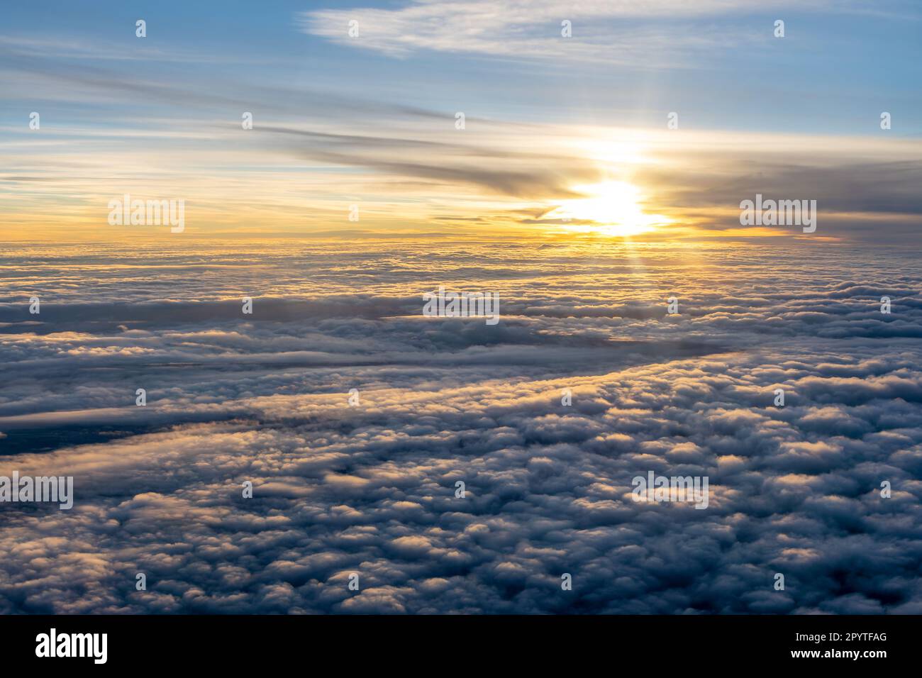 Soleil au-dessus d'une mer de nuages vus à travers la fenêtre de l'avion au coucher du soleil Banque D'Images