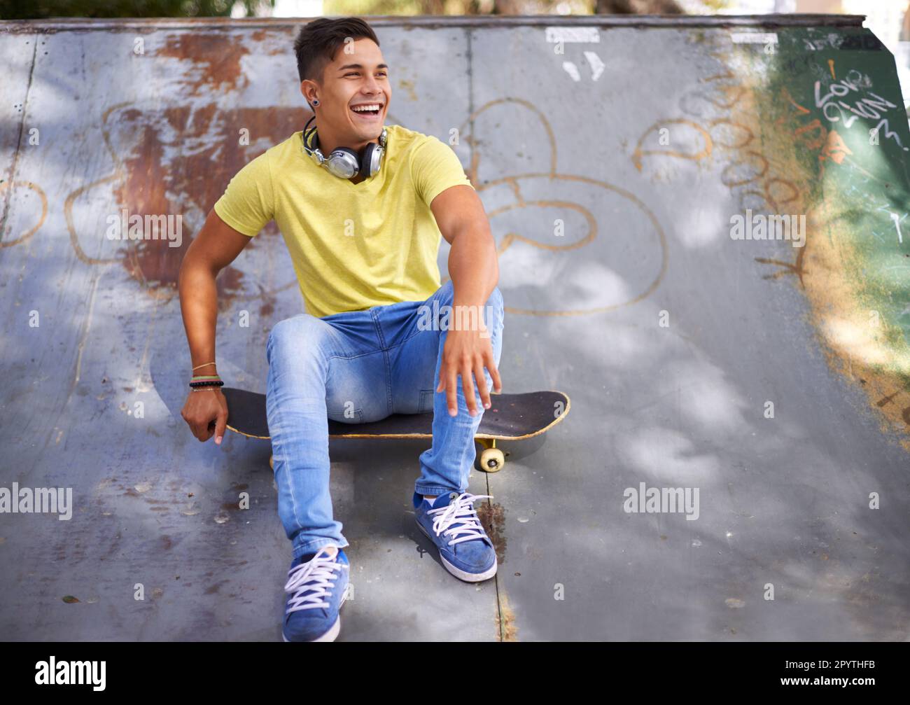 Dévalez la journée au skate Park. un jeune skateboarder se détendant dans un parc de skate. Banque D'Images