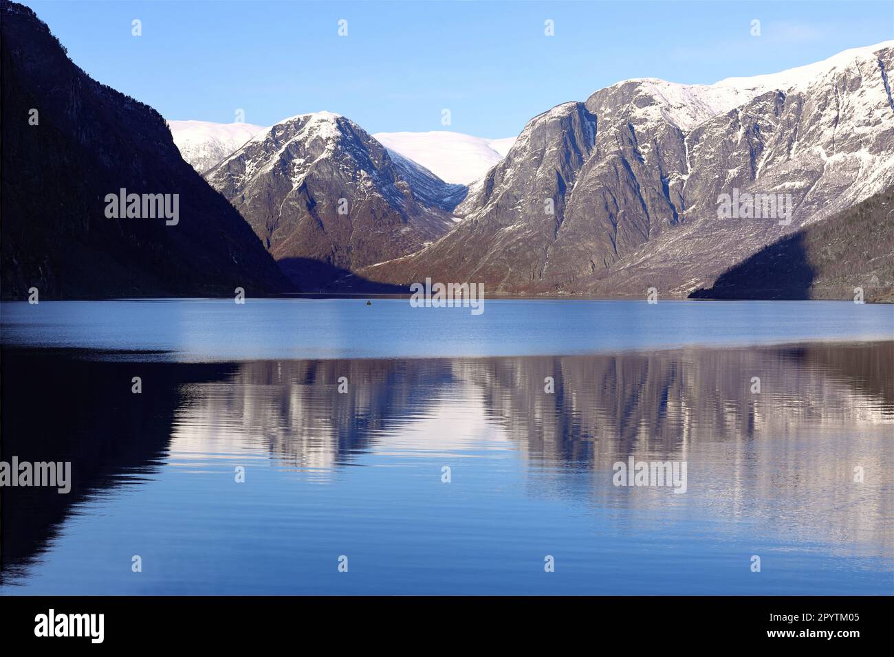 Village de Flam, Norvège - Aurlandsfjord et les montagnes enneigées environnantes se reflètent dans l'eau calme du fjord - ensoleillé avec un ciel bleu clair Banque D'Images