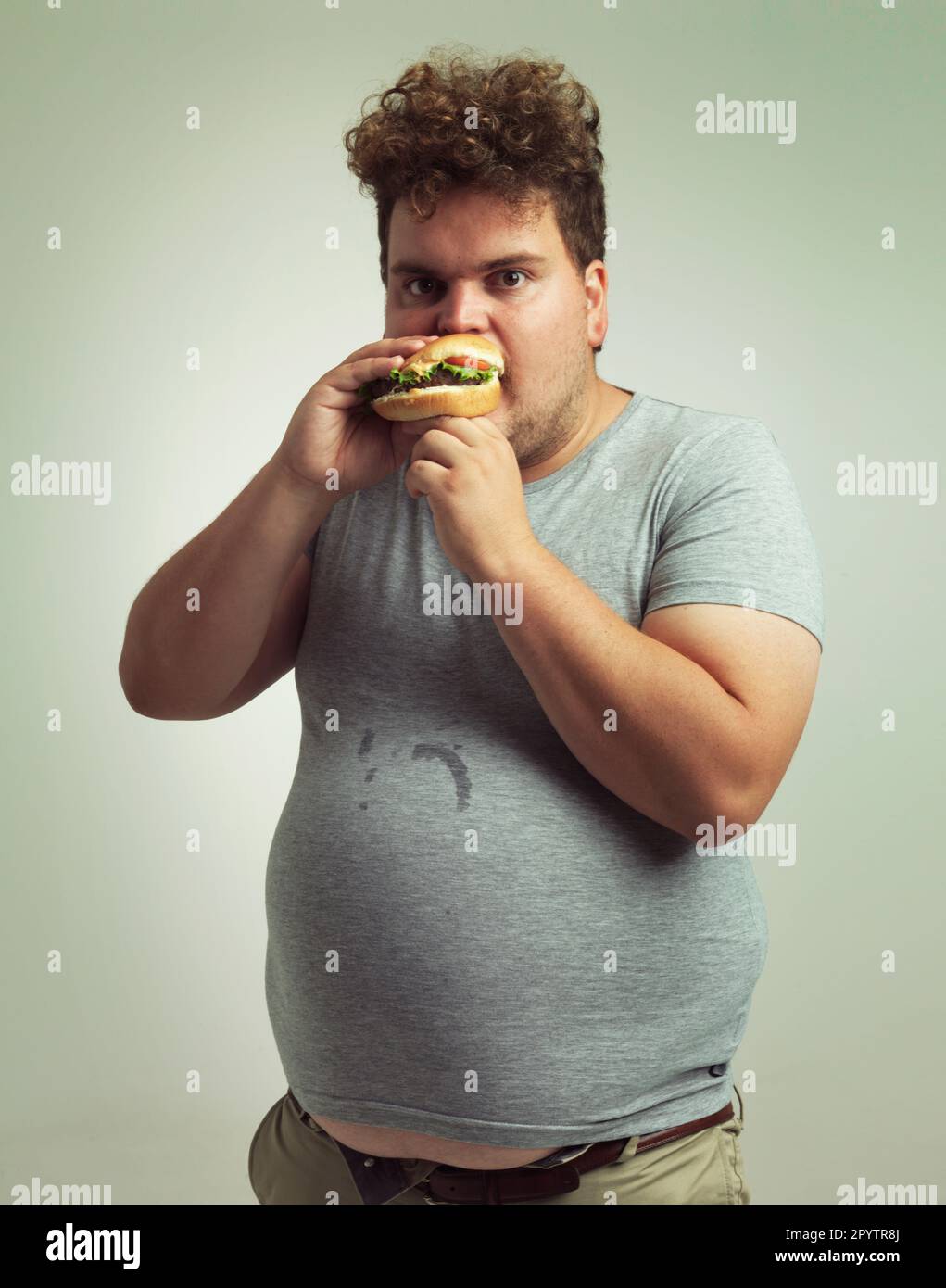Ce hamburger est le mien. Photo studio d'un homme en surpoids qui se mord dans un hamburger. Banque D'Images