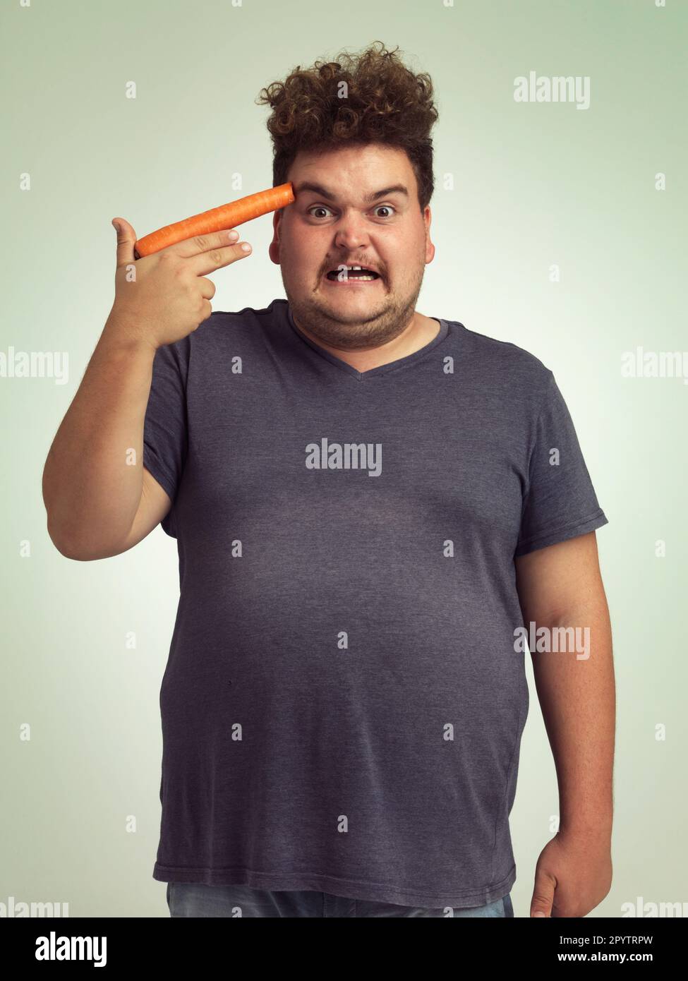 Perdre du poids ou mourir. un homme en surpoids tenant une carotte à sa tête. Banque D'Images