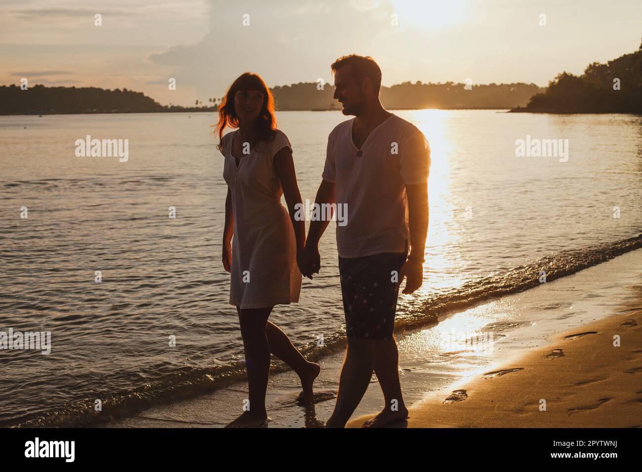 couple romantique marchant sur la plage, vacances de lune de miel, silhouettes d'homme et de femme tenant les mains Banque D'Images