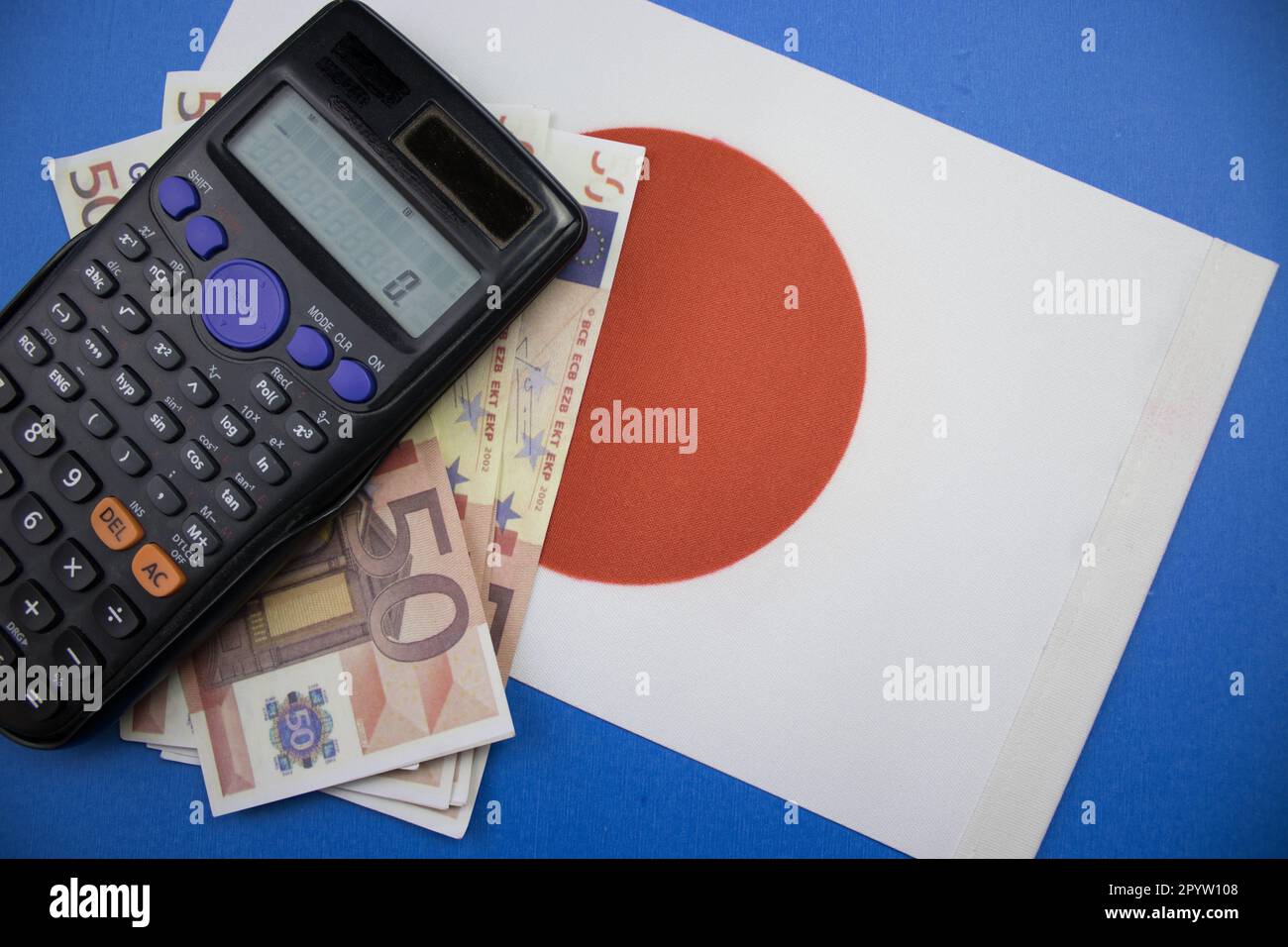 Le drapeau japonais placé sur fond bleu, des euros et une calculatrice. il a été photographié d'en haut. Banque D'Images