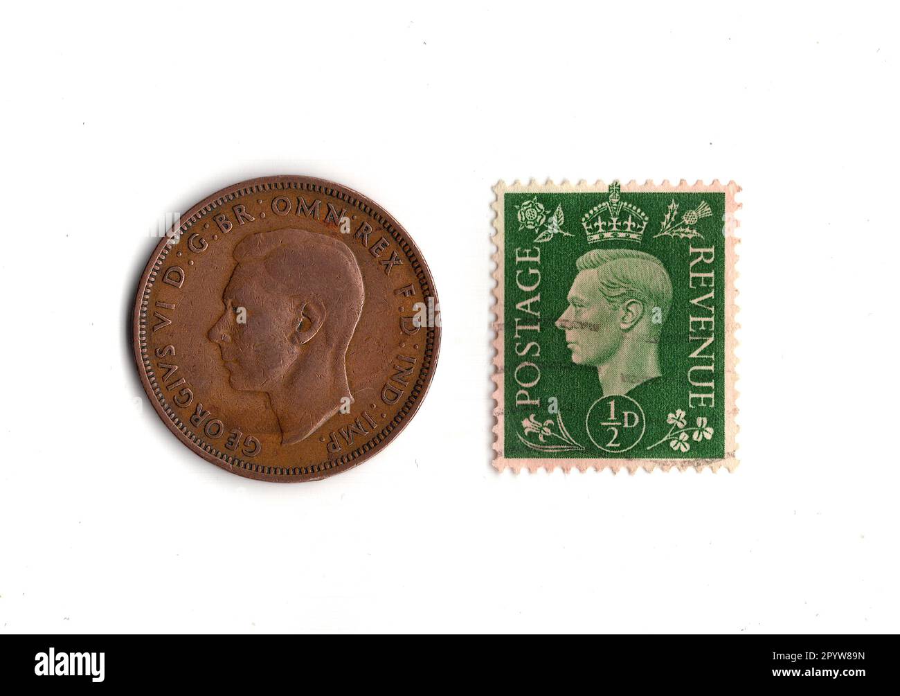 Pièce de monnaie à moitié penny et timbre du règne du roi George VI isolé sur un fond blanc. Banque D'Images