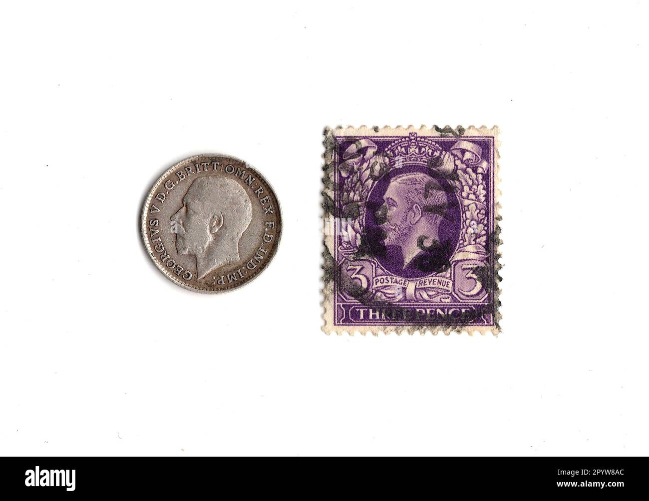 Pièce de Threepence et timbre du règne du roi George V isolé sur fond blanc. Banque D'Images