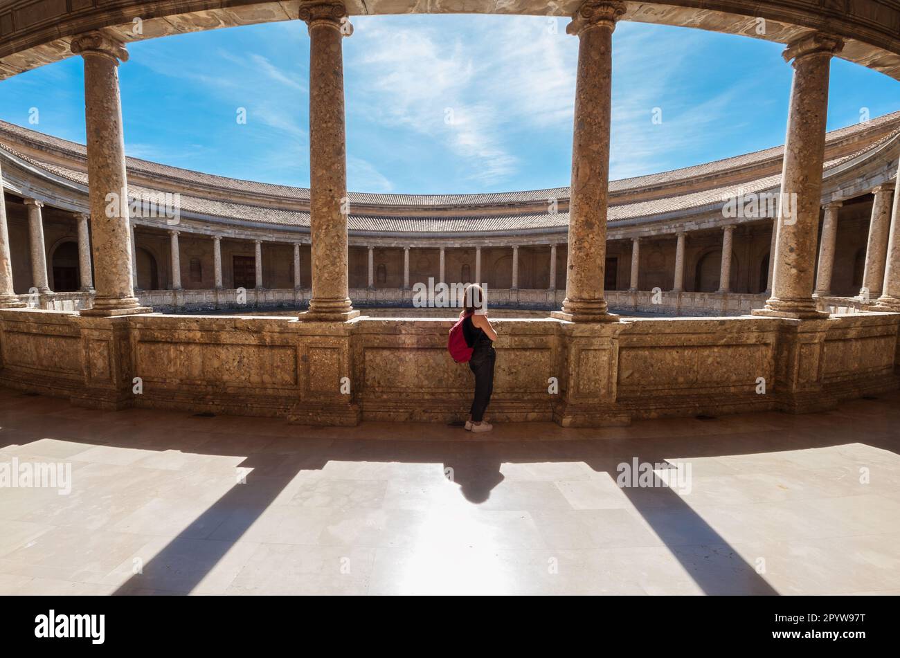 Jeune touriste femelle avec sac à dos en appréciant de grandes galeries avec des colonnes dans le patio circulaire intérieur dans le palais de Charles V dans le complexe Alhambra à Gran Banque D'Images