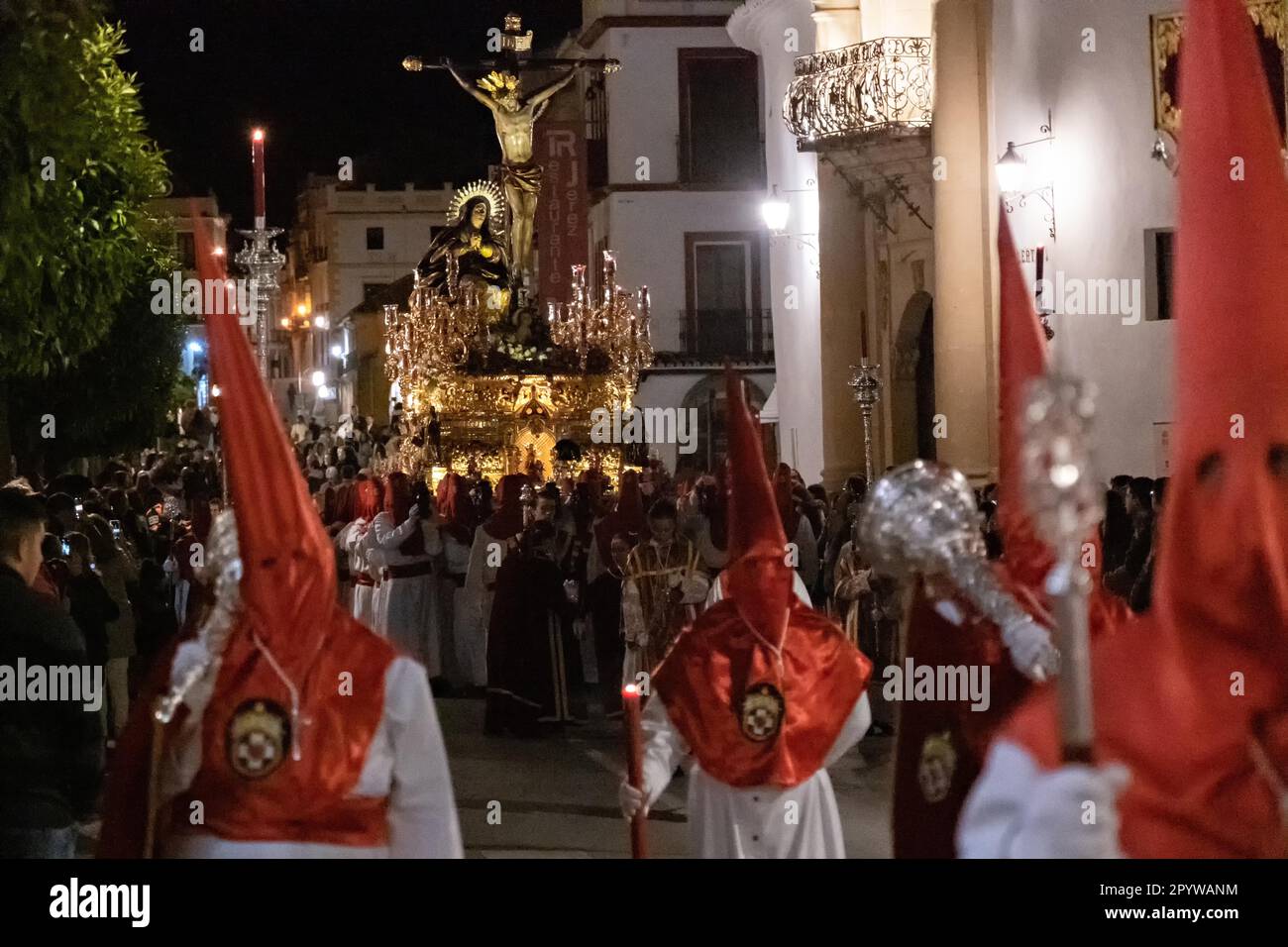 Les Cofradias portant des capuches en forme de cône rouge mènent une plate-forme géante avec la Crucifixion pendant la procession silencieuse de minuit marquant le Vendredi Saint à la semaine Sainte ou le Père Noël Semana, 6 avril 2023 à Ronda, Espagne. Ronda, établie pour la première fois au 6th siècle avant Jésus-Christ, organise des processions de la semaine Sainte depuis plus de 500 ans. Banque D'Images