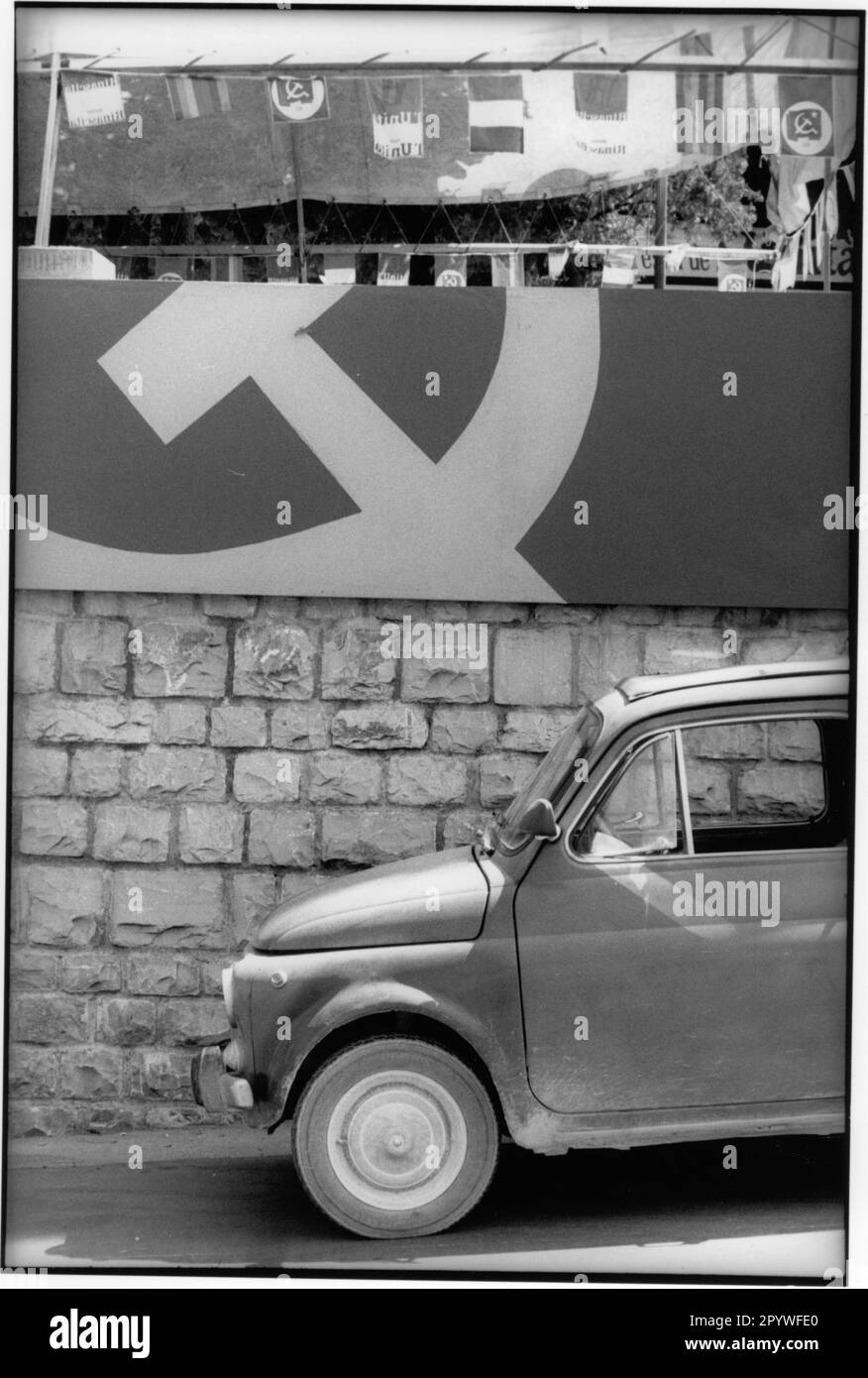' Toscane, Italie. Politique, élections. Élection des communistes et du journal communiste ''l'UNITA'': Décoration de drapeau avec marteau et faucille. Une Fiat 500 est garée devant le mur. Scène de rue, noir et blanc. Photo, 1988.' Banque D'Images