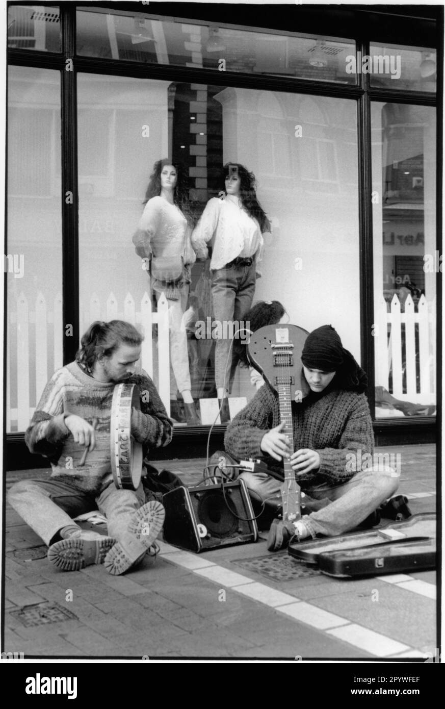 Irlande, Dublin. Société, musiciens de rue. Musicien de rue avec guitare électrique et tambourine devant une vitrine. Scène de rue, noir et blanc. Photo, 1992. Banque D'Images