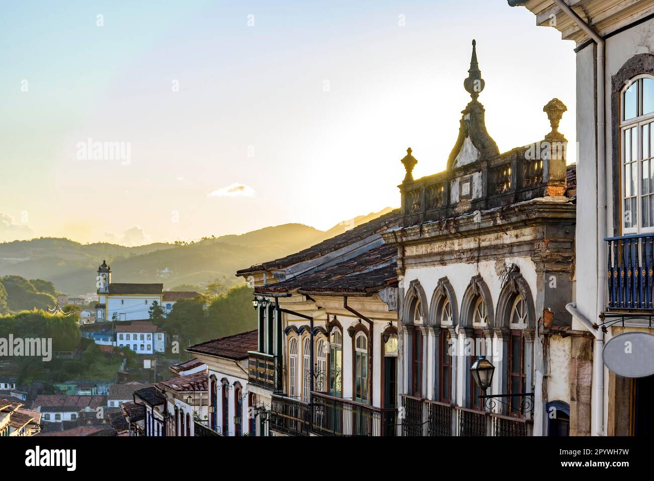 Vue sur les maisons de style colonial façade et église baroque historique en arrière-plan sur les collines de la ville d'Ouro Preto, état de Minas Gerais, Brésil, Brésil Banque D'Images