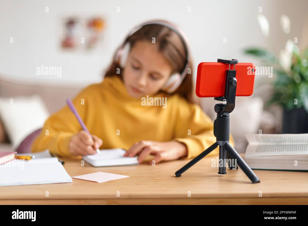École à distance, concept de homeschooling. Jeune fille étudiant à la maison en utilisant un smartphone, ayant cours en ligne avec professeur à distance. Éducation à domicile des enfants pendant le coronavirus. Concentrez-vous sur votre smartphone Banque D'Images