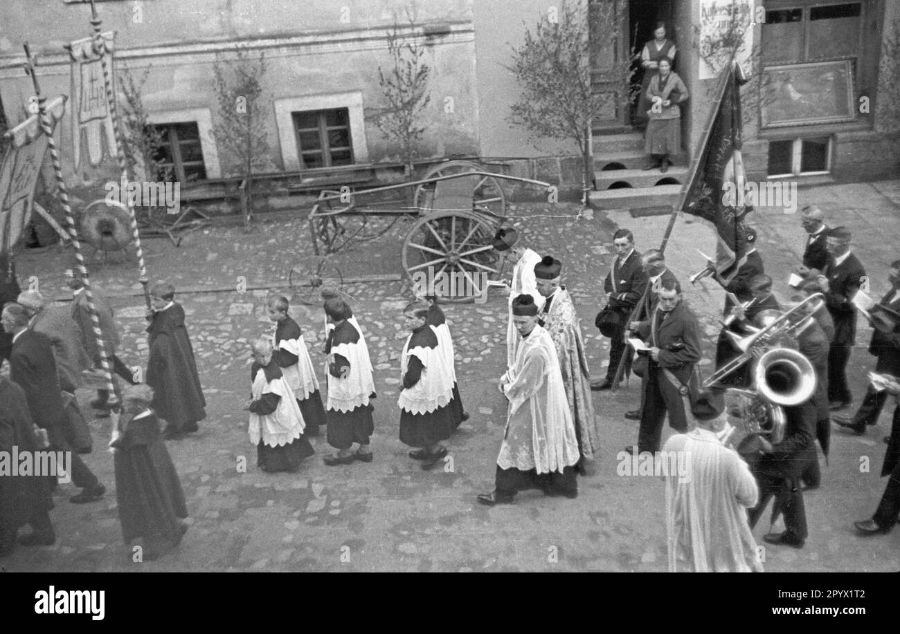 Le pasteur de l'église de pèlerinage de Mariae Heimsuchung (visite de la Sainte Vierge Marie) mène une procession dans les rues de l'Albendorf silésien. La photo montre les ministrants, les porteurs de drapeau et les joueurs de laiton. Banque D'Images