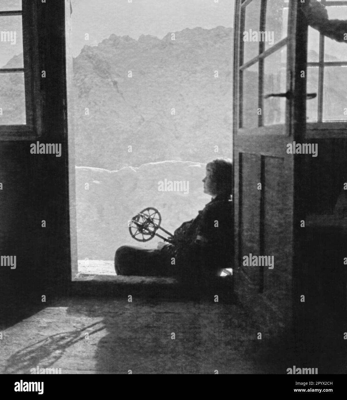 Un participant fait un arrêt à l'entrée d'une cabane de montagne et profite du soleil. Photo non datée, probablement à la mi-1930s. Banque D'Images