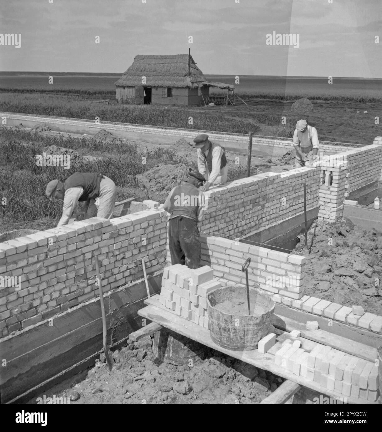 Les travailleurs construisent un mur de briques silico-calcaires pour séparer les chantiers. Photo non datée, probablement prise en 1934. [traduction automatique] Banque D'Images