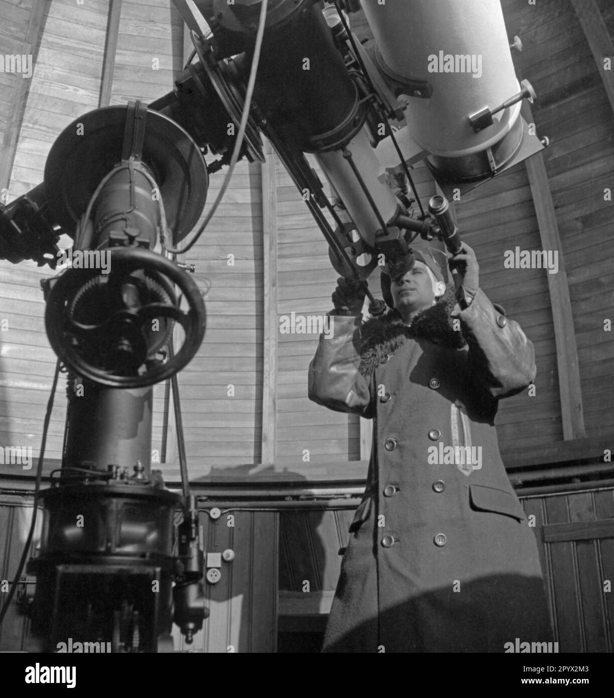 Un employé regarde à travers un télescope. C'était le premier télescope de l'Observatoire de Sonneberg. Il s'agit d'un télescope à 135mm objectifs avec des caméras célestes d'une ouverture de 170, 140 et 78 millimètres (de droite à gauche). Photo non datée, probablement en 1930s. Banque D'Images