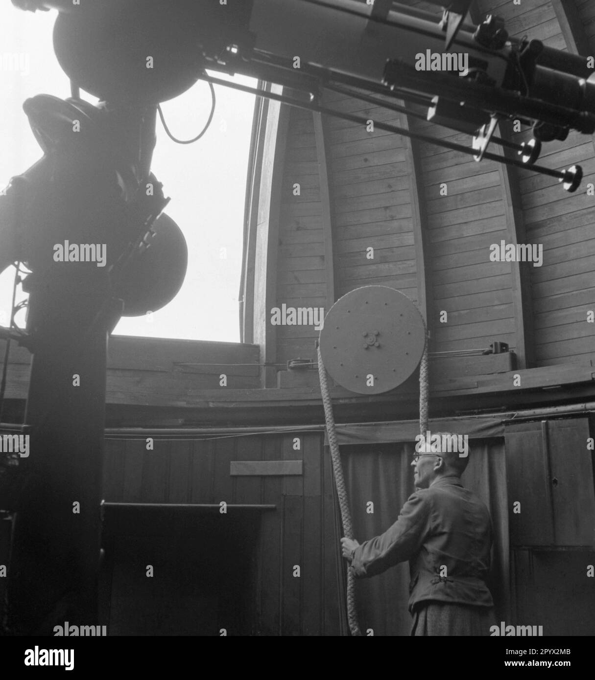 L'employé ouvre la trappe de l'observatoire avec un câble. Au premier plan se trouve le réfracteur 135mm. Photo non datée, probablement en 1930s. Banque D'Images