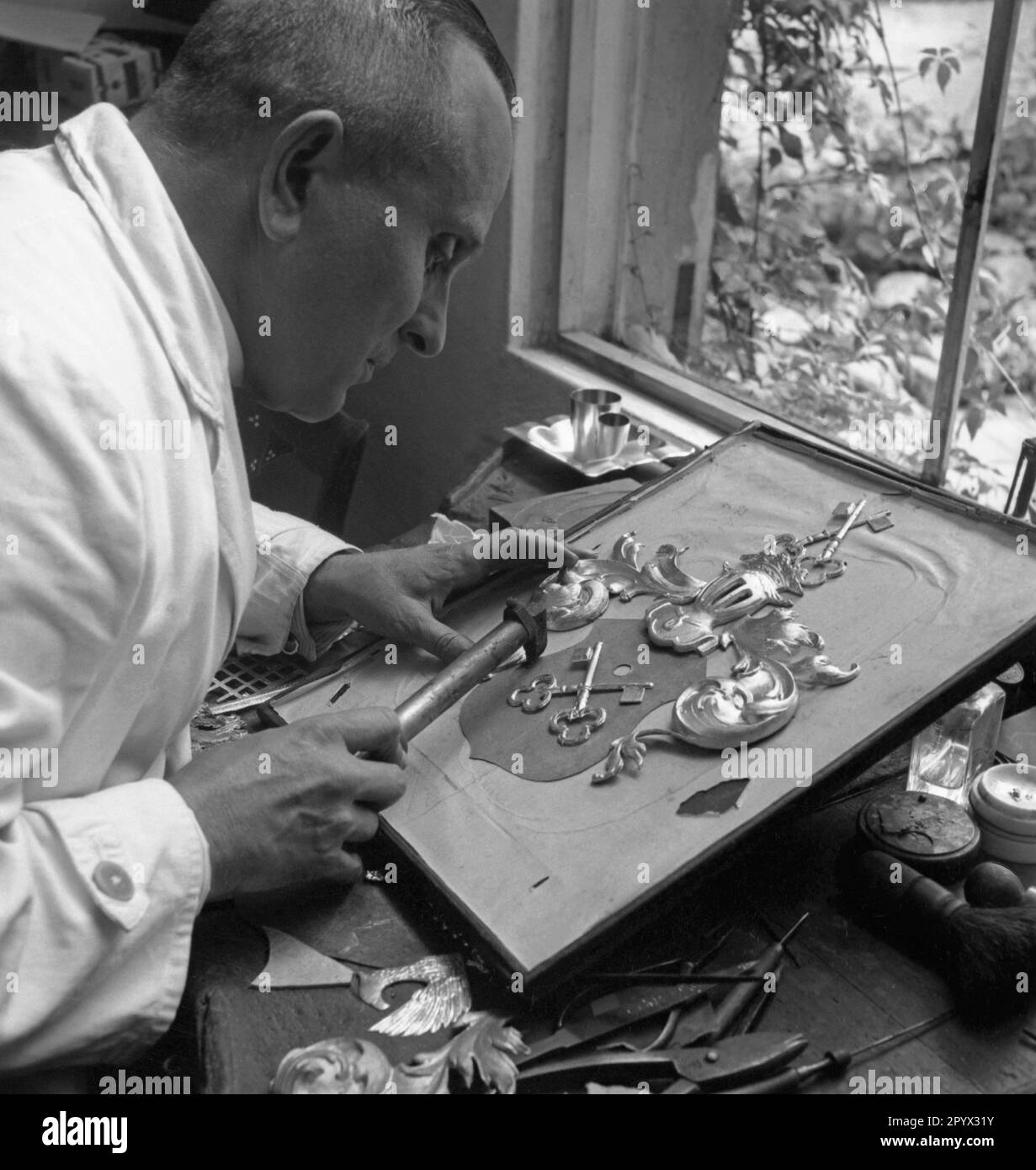 Un artisan fait un manteau de bras avec clé en métal. Banque D'Images