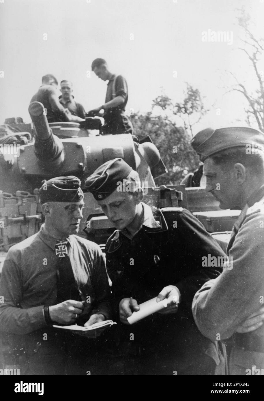 Détenteur de la Croix de Chevalier Premier lieutenant Ernst-Georg Buchterkirch (à gauche), Panzer Regiment 6, lors d'un exposé de situation avec d'autres officiers de Wehrmacht dans un village biélorusse dans la partie centrale du Front de l'est. En arrière-plan, un Panzer III [traduction automatique] Banque D'Images