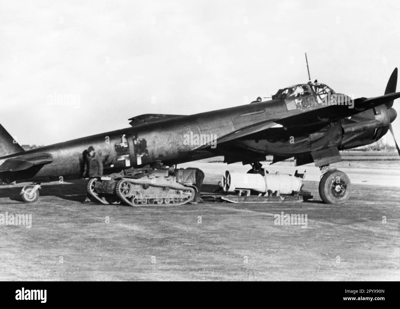 Un avion de chasse allemand Junkers Ju 88 est chargé de bombes pour une mission contre des cibles en Angleterre. Le train de roulement d'un réservoir français sert de tracteur. L'avion est peint avec une peinture de camouflage sombre, la croix de faisceau est également en partie de couleur foncée. Photo : Rempel. [traduction automatique] Banque D'Images